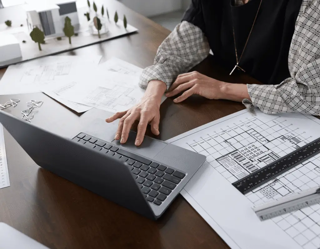 Someone working on a laptop with blueprints